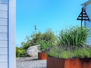 A garden with a large rock, a metal sculpture, and a building with a white exterior. - 2 Person Holiday Home in Marstrand (Marstrand)