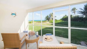 Una habitación con un ventanal grande, muebles de mimbre y vistas al océano.