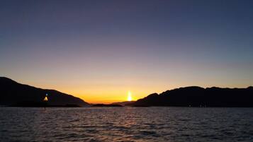 A sunset over a body of water with distant landforms.