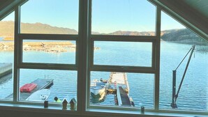 Blick aus einem Zimmer mit großen Fenstern auf einen Yachthafen mit Booten und eine ferne Bergkette.