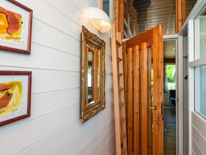 A hallway with white paneling, a wooden door, and two framed artworks on the wall.