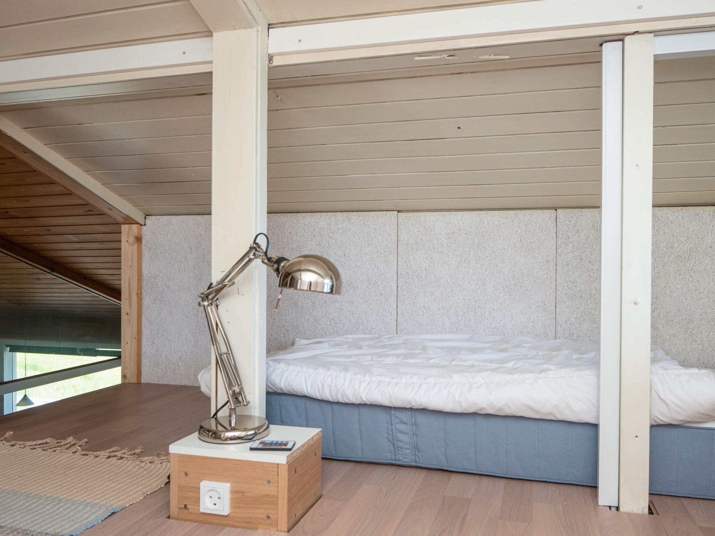 A compact room with a bunk bed, a desk with a lamp, and a power outlet.