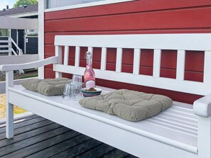 A white bench with cushions and a bottle of Effervescent on it.