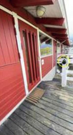 A red building with a wooden deck and a door.