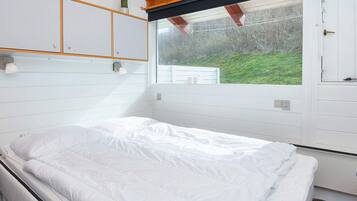 A bedroom with a bed, a window, and a view of the outdoors.