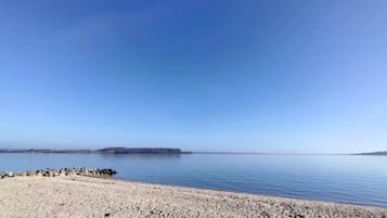 Uma praia com céu claro e águas calmas.