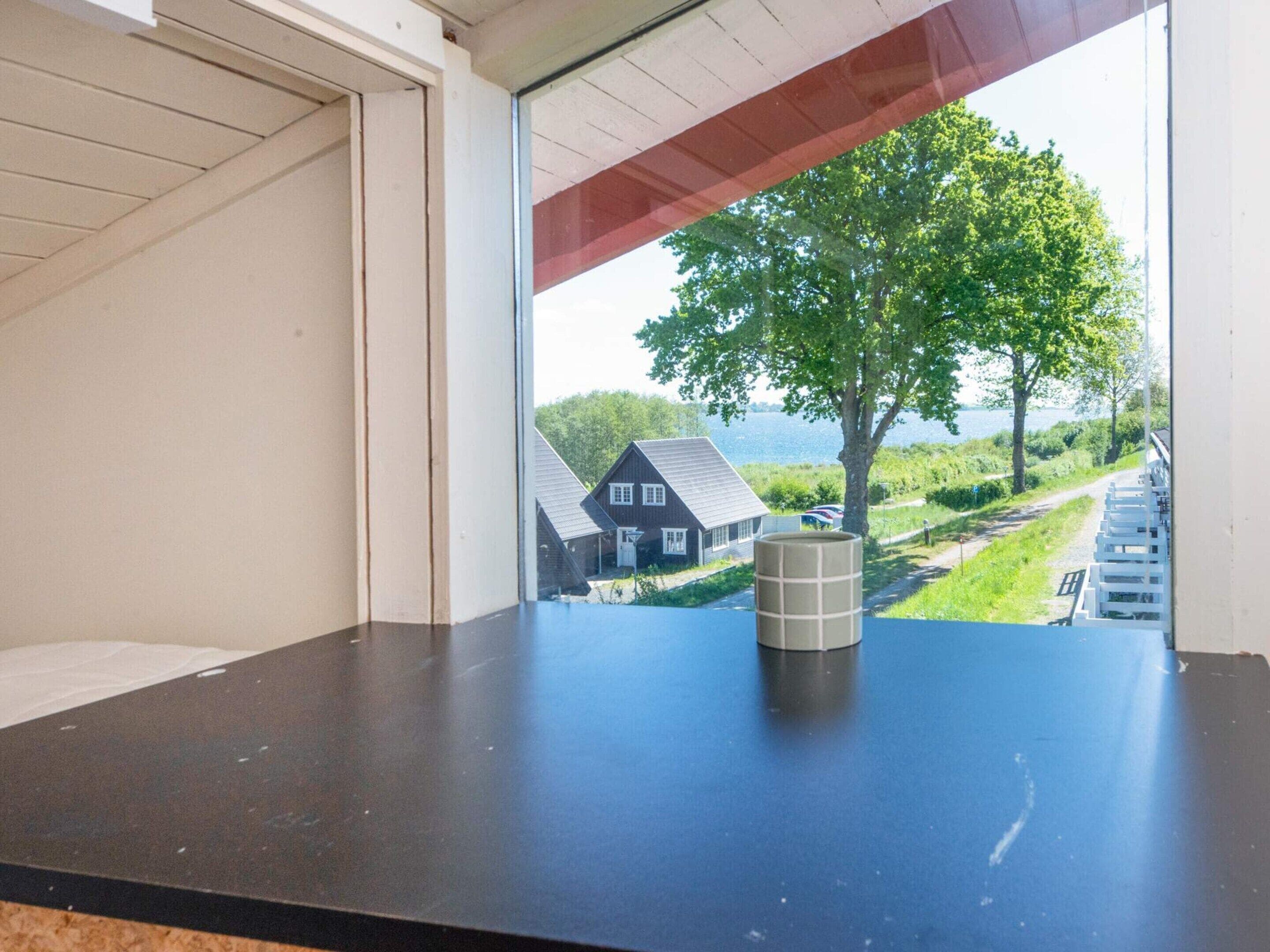 A room with a view of a house and a tree through a window.