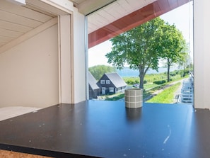 Quarto com vista para uma casa e uma árvore através de uma janela.
