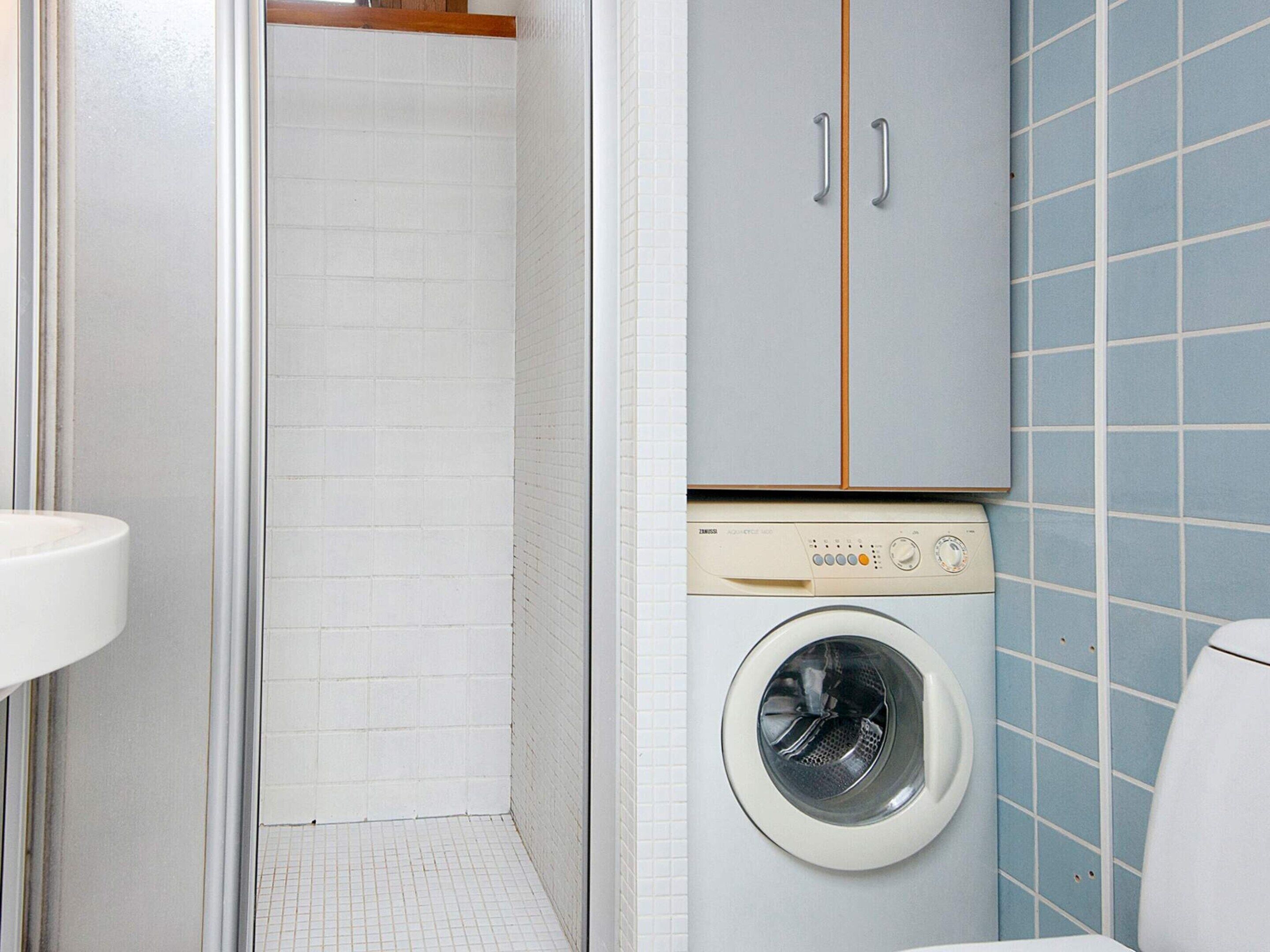 Casa de banho compacta com máquina de lavar roupa, sanita e lavatório.