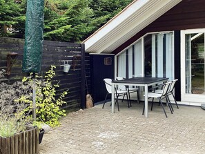 A patio with a table and chairs, a wooden fence, and a sliding glass door. - 4 Person Holiday Home in Vaeggerlose (Vaeggerlose)