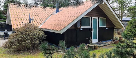 Een klein houten huisje met schuine dak en raam.