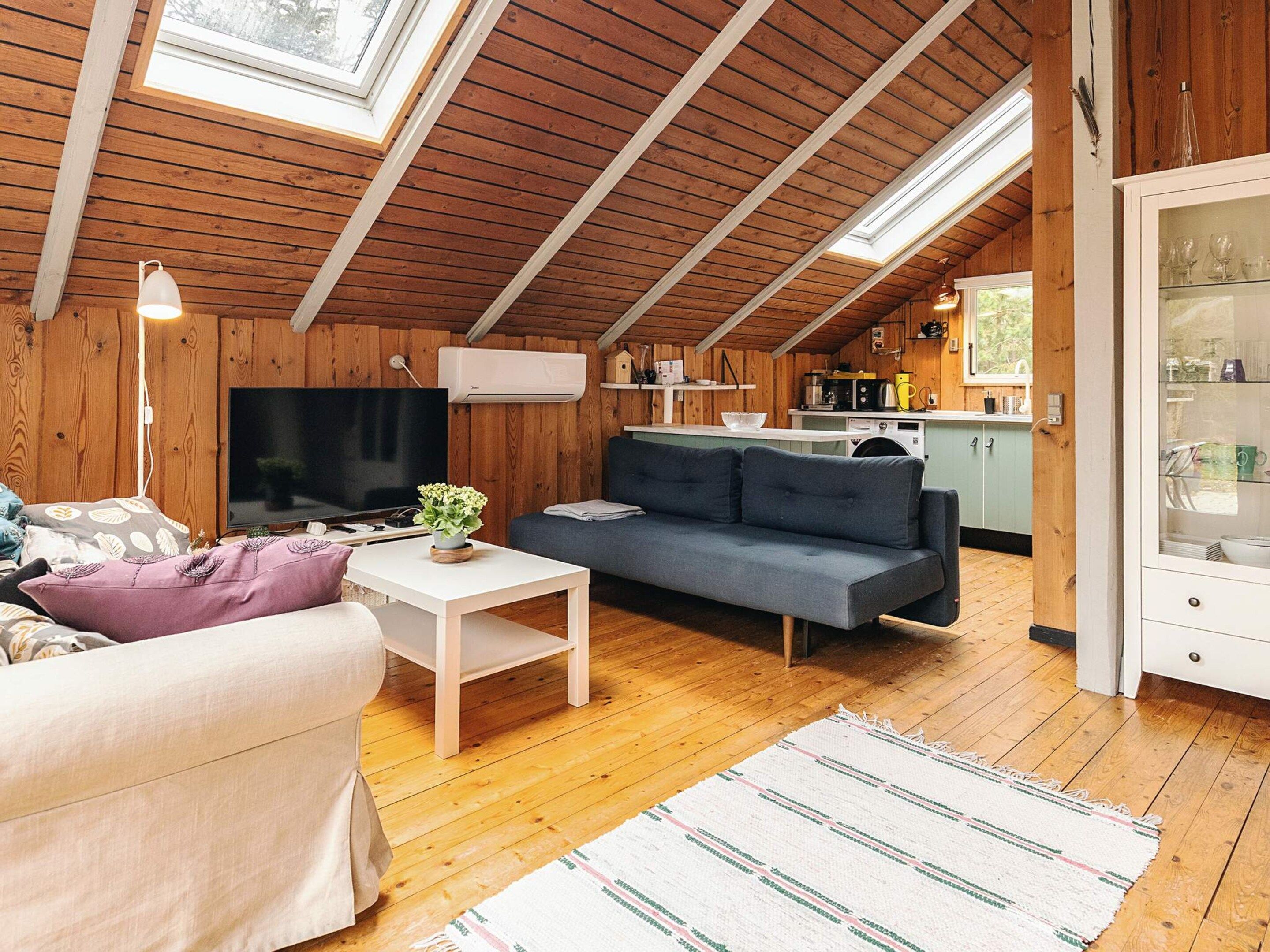 A cozy living room with a sofa, a television, and a dining area with a table and chairs.