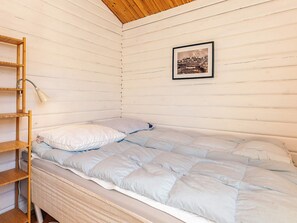 Una cama individual con una colcha acolchada, una escalera de madera y un cuadro en la pared.
