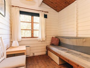 A cozy cabin interior with a wooden bench, a table, and a window with curtains.