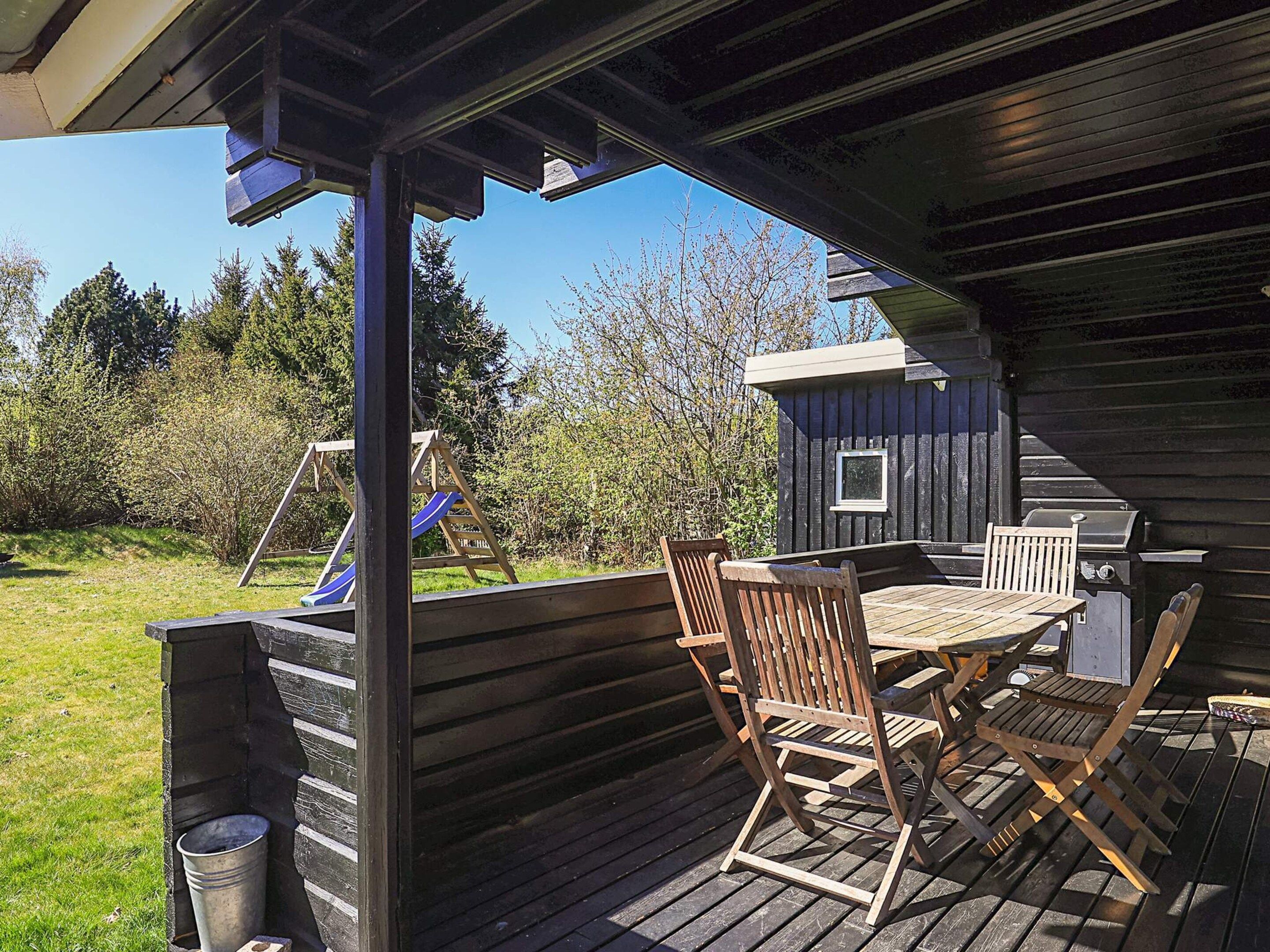 An outdoor deck with a table and chairs, a grill, and a play structure.