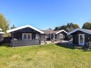 A row of wooden cabins with a grassy yard and a clear blue sky.