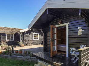 Eine Holzhütte mit einer Veranda, einer Eingangstür und einer kleinen Sitzgelegenheit im Freien.