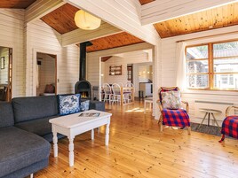 A cozy living room with a fireplace, wooden floors, and a dining area with white furniture.