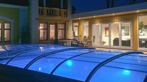 A large glass-enclosed pool with a blue tint, surrounded by a wooden deck and outdoor furniture. - 10 Person Holiday Home in Arendal-by Traum (Arendal)