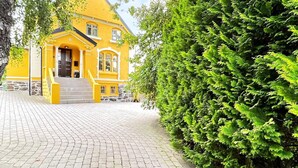 A yellow house with a stone foundation, a brick pathway, and a large green bush. - 10 Person Holiday Home in Arendal-by Traum (Arendal)