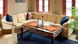 Una sala de estar con un sofá color beige, una mesa de centro de madera y una alfombra azul.