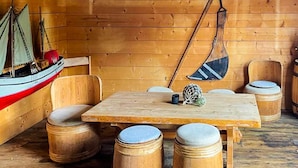 Un interior de madera con una mesa y sillas, una hamaca colgante y un modelo de barco.