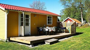 Ein gelbes Haus mit rotem Dach, einer Veranda mit Stühlen und einem kleinen Tisch.