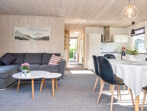 Een modern interieur met een grijze bank, een ronde salontafel en zwarte stoelen.
