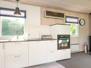A modern kitchen with white cabinetry, a built-in oven, a stainless steel sink, and a clock on the wall. - 5 Person Holiday Home in Bording (Bording)