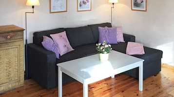 A living room with a dark-colored sofa, two purple pillows, a white coffee table, and a wooden cabinet.