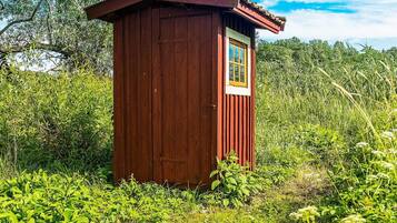 A small wooden structure with a door and a window, surrounded by dense vegetation.