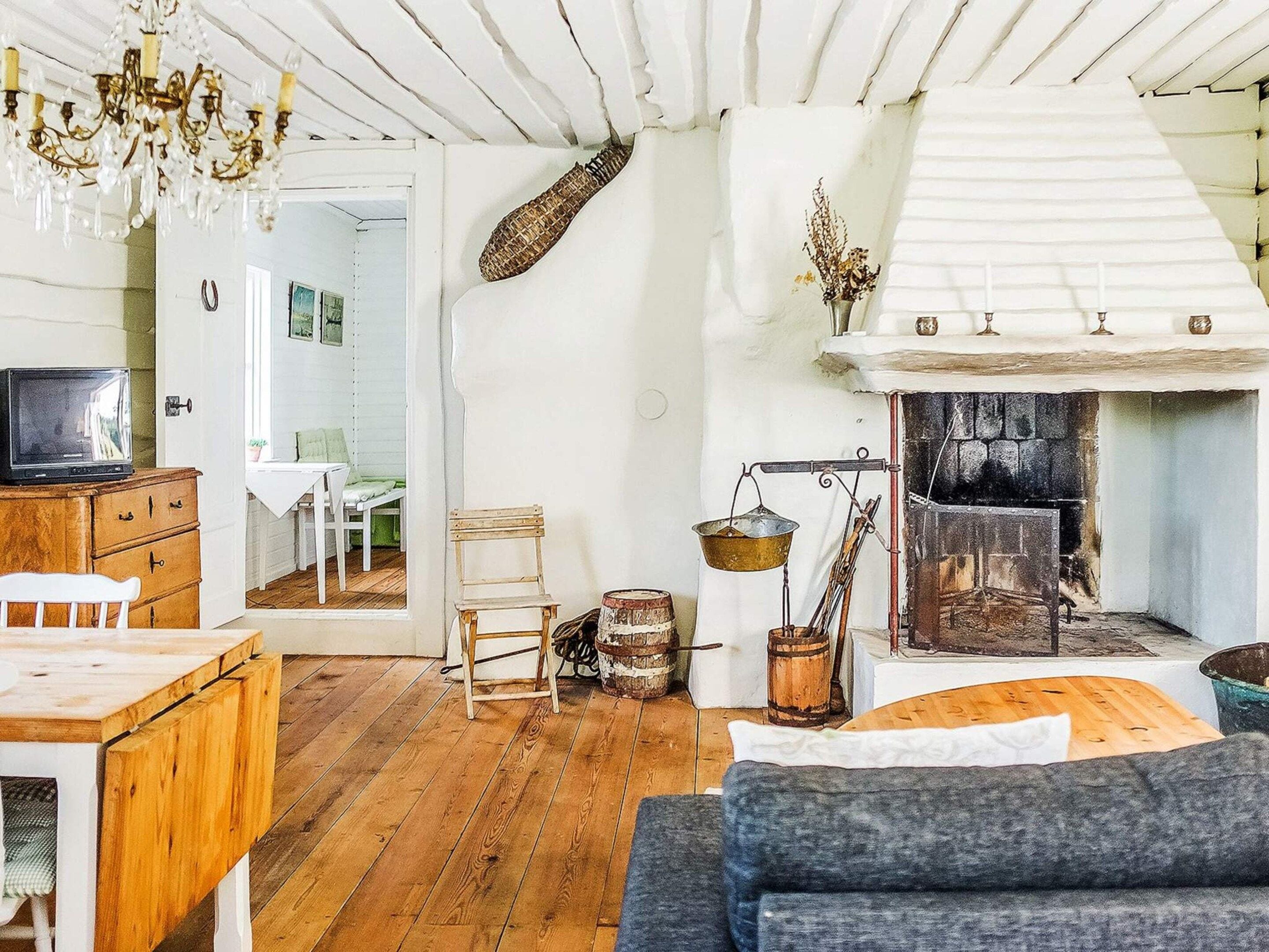 Een gezellige woonkamer met een open haard, houten meubels en een kroonluchter.