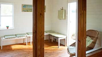 A room with wooden floors, a bench, a chair, and a window with a plant.