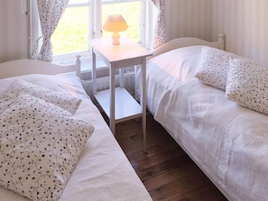 A bedroom with two beds, a small table with a lamp, and a window with curtains. - 5 Person Holiday Home in Flen (Flen)