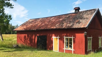 A red wooden building with a sloped roof, a door, and windows.