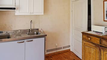 A compact kitchen with white cabinets, a stainless steel sink, and a wooden cabinet with a toaster.