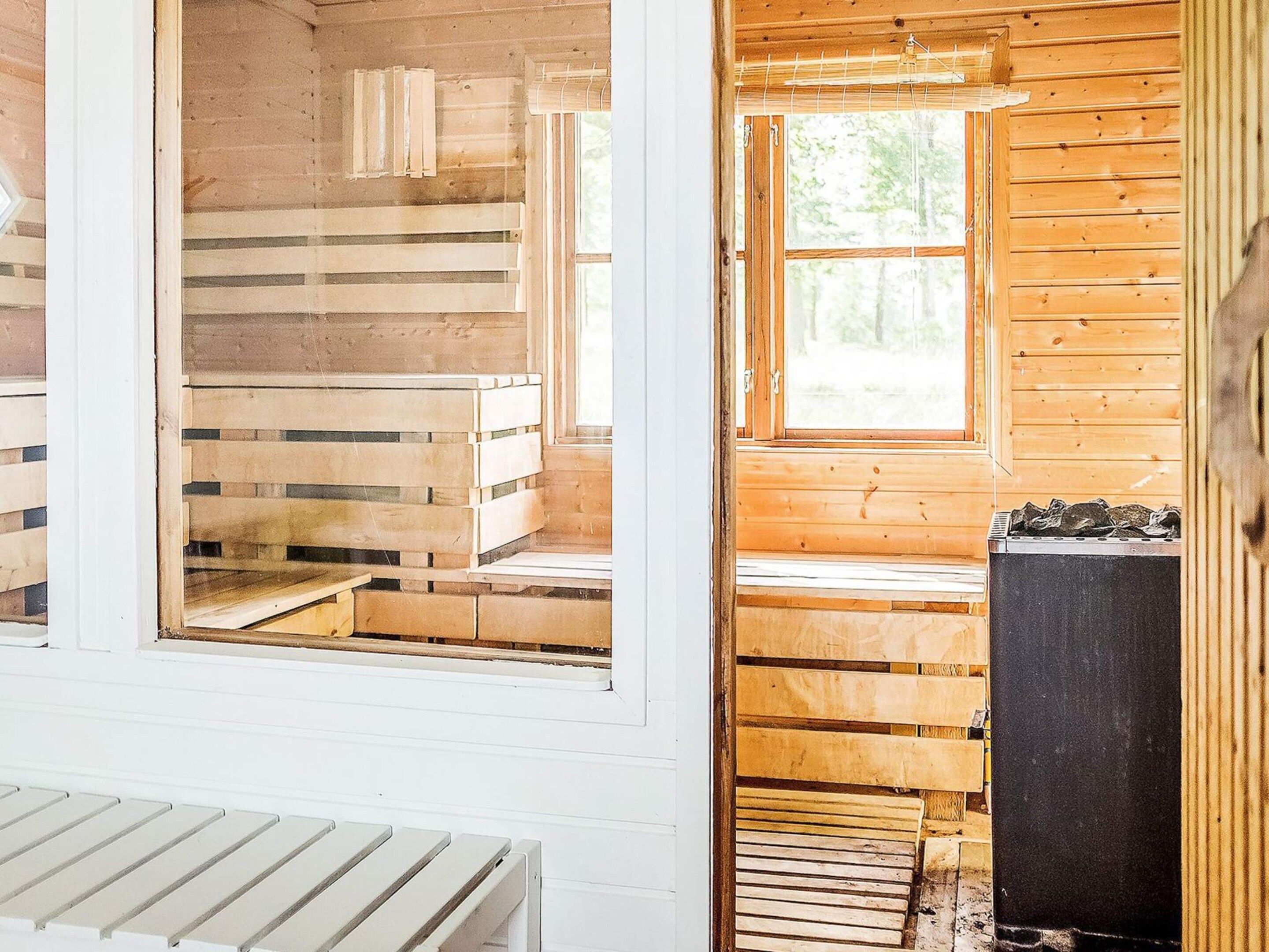 A wooden cabin interior with a bench, a window, and a fireplace.