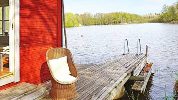 A wooden dock extending into a body of water with a wicker chair on it.