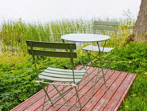 A wooden deck with a table and two chairs by a body of water.
