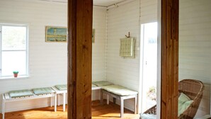 A room with wooden floors, white walls, and a bench with a cushion. There is a window with a plant on the sill. - 5 Person Holiday Home in Flen (Flen)