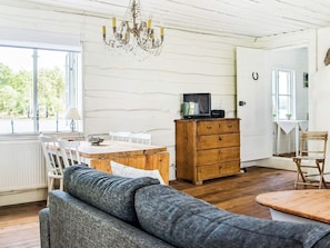 A cozy room with a wooden dining table, a sofa, a wooden dresser, and a chandelier. - 5 Person Holiday Home in Flen (Flen)