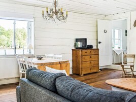 Una habitación acogedora con una mesa de comedor de madera, un sofá, un aparador de madera y una araña.
