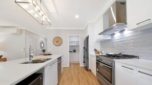 Uma cozinha moderna com armários brancos, fogão de aço inoxidável e piso de madeira.