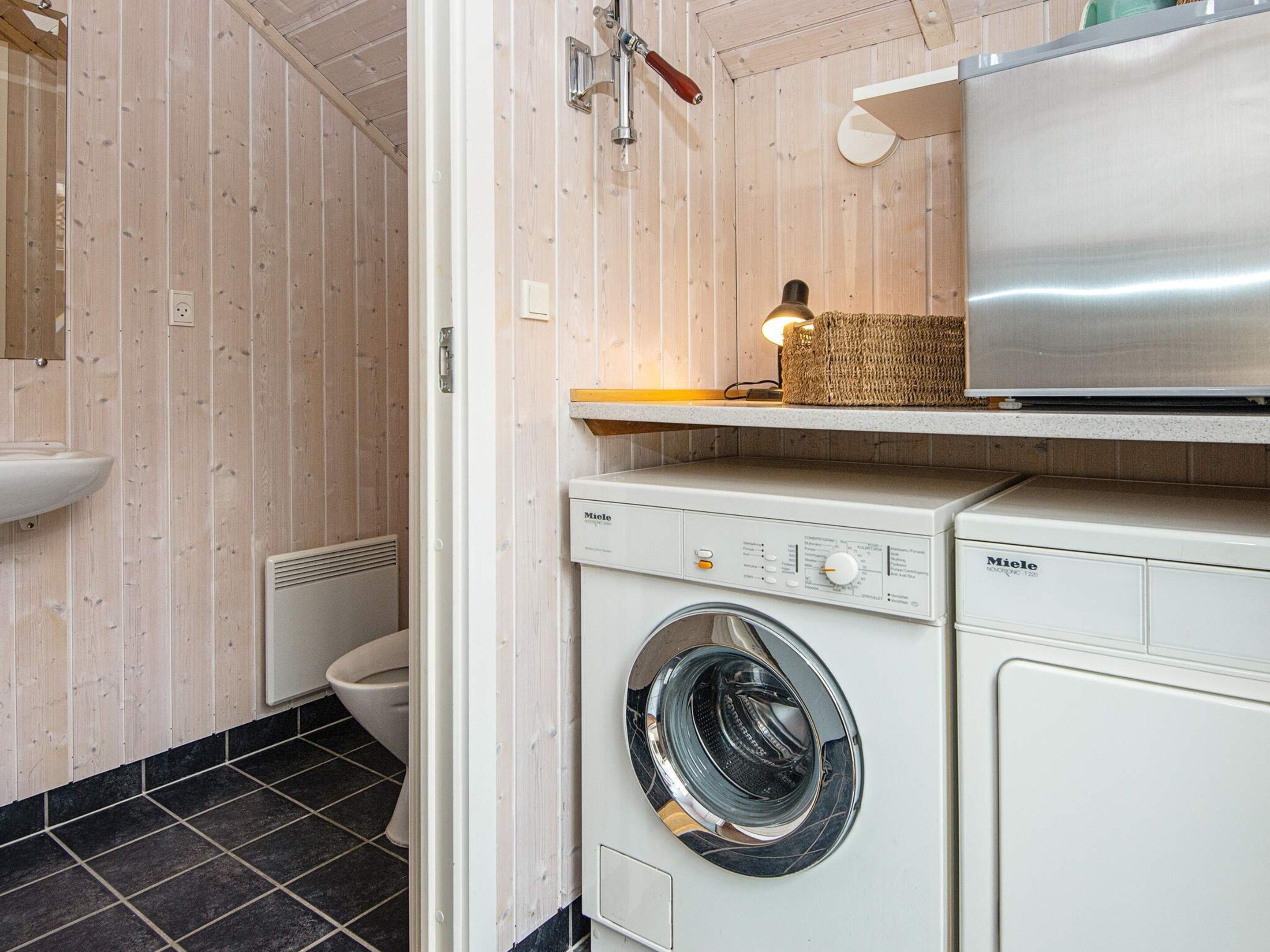 A compact laundry room with a washing machine, a dryer, and a small shelf with a basket.