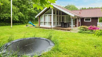 A house with a covered patio, a trampoline, and a slide in the yard.
