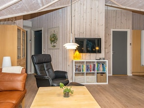 A living room with a leather sofa, a wooden coffee table, a black armchair, a bookshelf, and a television mounted on the wall. - 7 Person Holiday Home in Toftlund-by Traum (Toftlund)