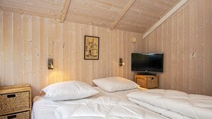 Et værelse med træpaneler, en seng, et fjernsyn og et billede i ramme på væggen.