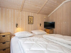 Una habitación con paneles de madera, una cama, un televisor y un cuadro en la pared.