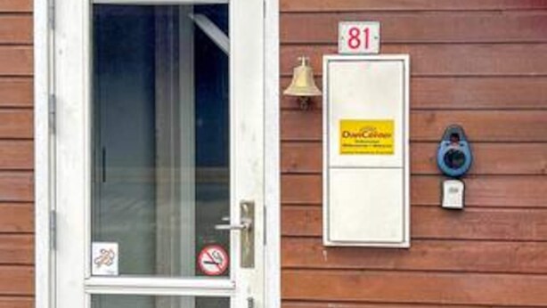 En træfacade med en dør, et postkasse og en ringeklokke.