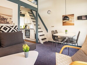 A compact living space with a kitchenette, a dining area, and a staircase.